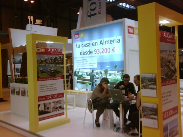 Ein Raum mit Menschen, die an einem Tisch arbeiten, umgeben von Flyern mit verschiedenen Werbeanzeigen.