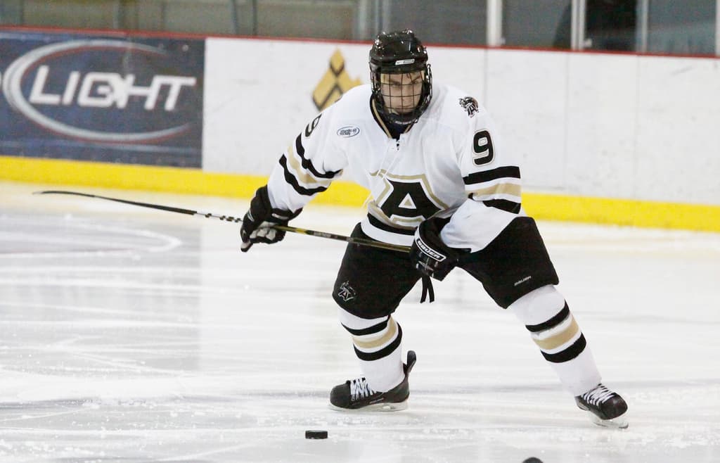 Eine Person fährt Eislauf mit einer Wand im Hintergrund.