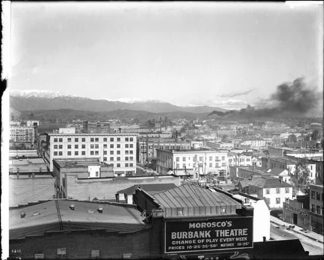 Ein Schwarz-WeiÃŸ- Bild einer Fabrik mit Rauch, der aus dem Schornstein kommt, umgeben von GebÃ¤uden.