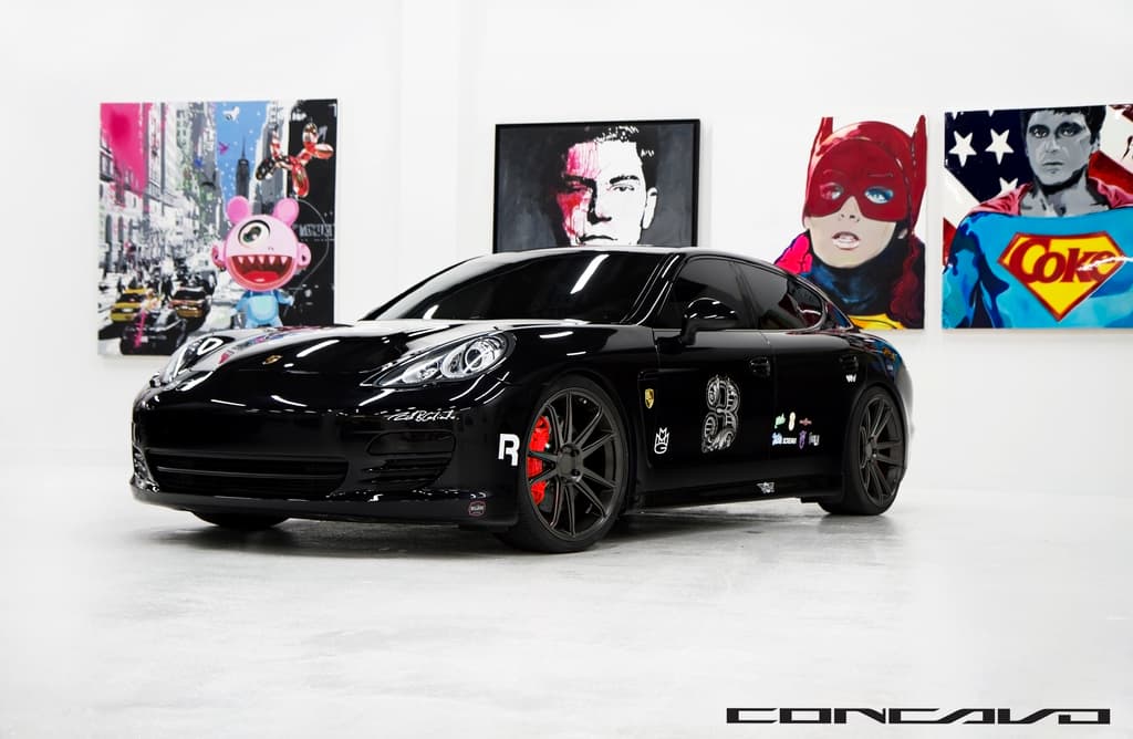 Ein schwarzer Nissan-Sportwagen steht vor Cartoon-Postern, mit einer kleinen Inschrift am unteren Rand des Bildes.