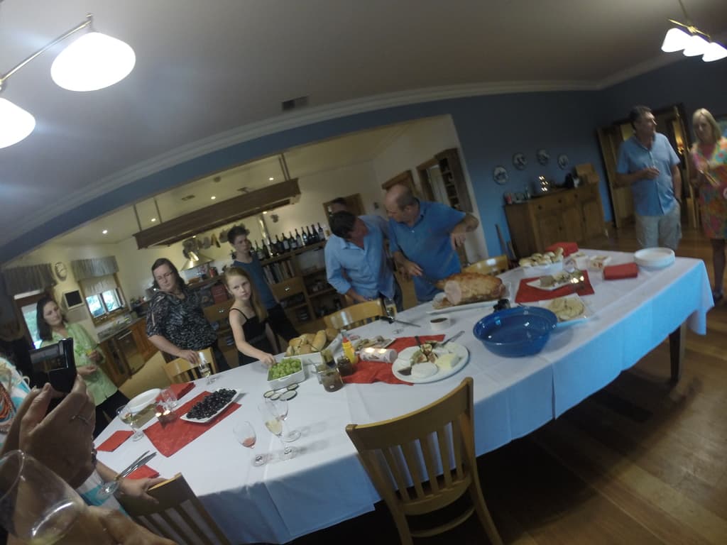 Eine Gruppe von Menschen steht in einem Raum mit einem weißen Mitteltisch, der mit Essen bedeckt ist.