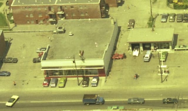 Eine Luftaufnahme einer Stadt mit zahlreichen Autos um Gebäude herum und einigen Autos auf der Straße.