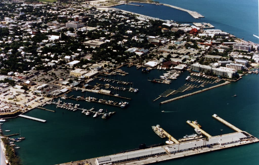 Eine Vogelperspektive einer Stadt mit vielen Gebäuden, Meerwasser und einem Hafen mit einigen Schiffen im Vordergrund.