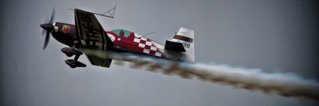 Ein rotes Flugzeug mit Entwürfen darauf, das durch die Luft fliegt und eine Rauchspur hinterlässt.