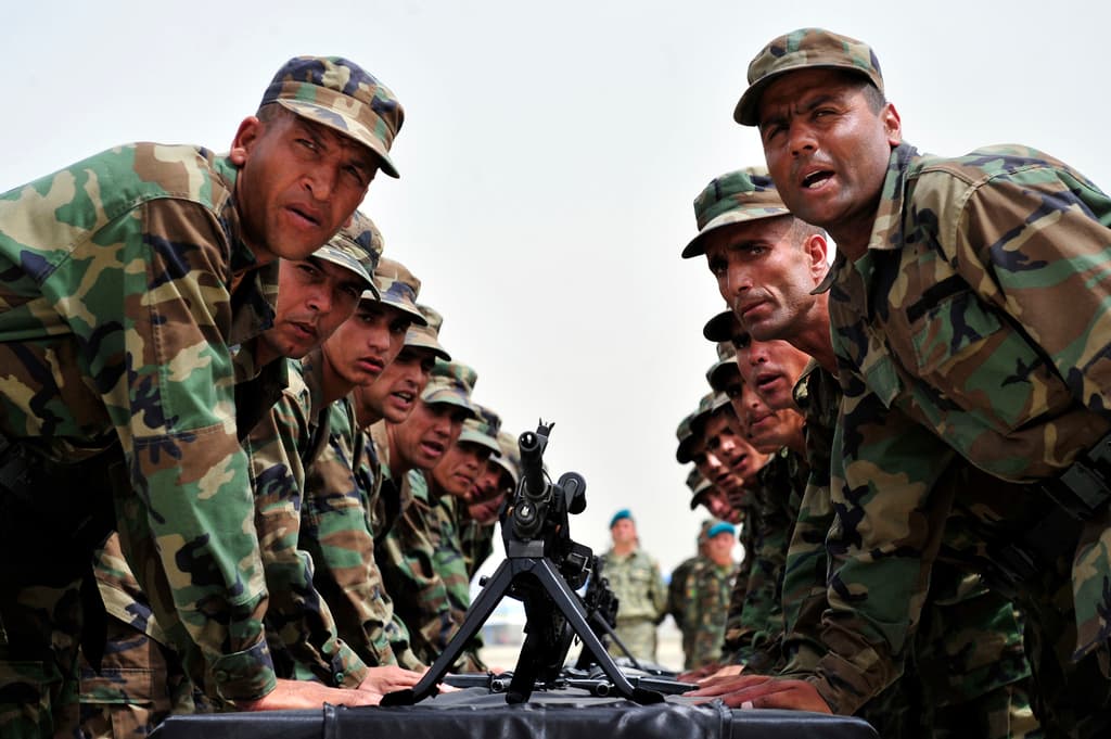 Eine Gruppe von Soldaten steht um einen Tisch mit einer Waffe darauf.