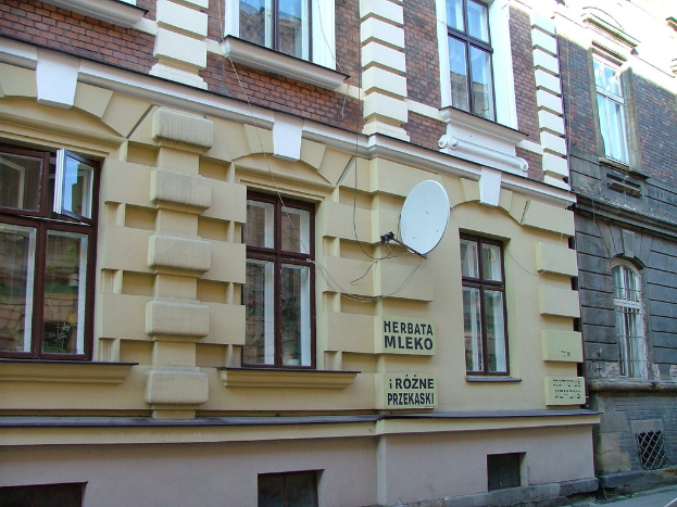 Ziegelgebäude mit Glasfenstern, Graffiti an den Wänden und eine Satellitenschüssel auf einer der Wände.