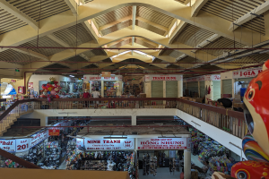 Ein belebtes Einkaufszentrum-Innere mit verschiedenen Gegenständen wie Spielzeug, Schildern, Geländern, Treppen und Lampen sowie einigen Menschen.