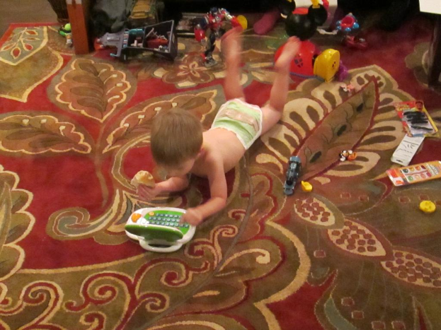 Ein Kind, das umgeben von verschiedenen Spielzeugen liegt.