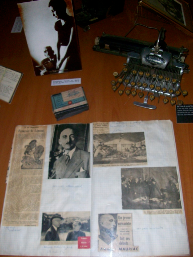 Eine hölzerne Plattform mit einem Buch, Plakaten, Fotos von Menschen, Karten, einem Foto und einer Maschine.