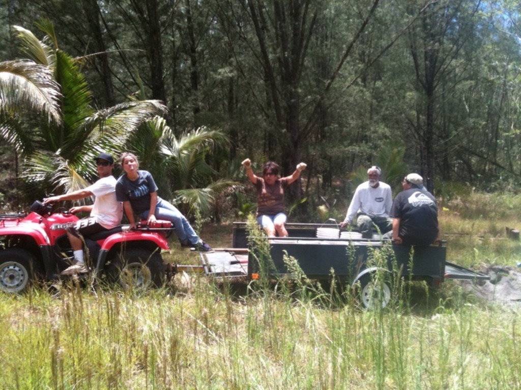 Eine Gruppe von Menschen auf einem Traktor mit einer Person, die es f√§hrt, mit B√§umen im Hintergrund.