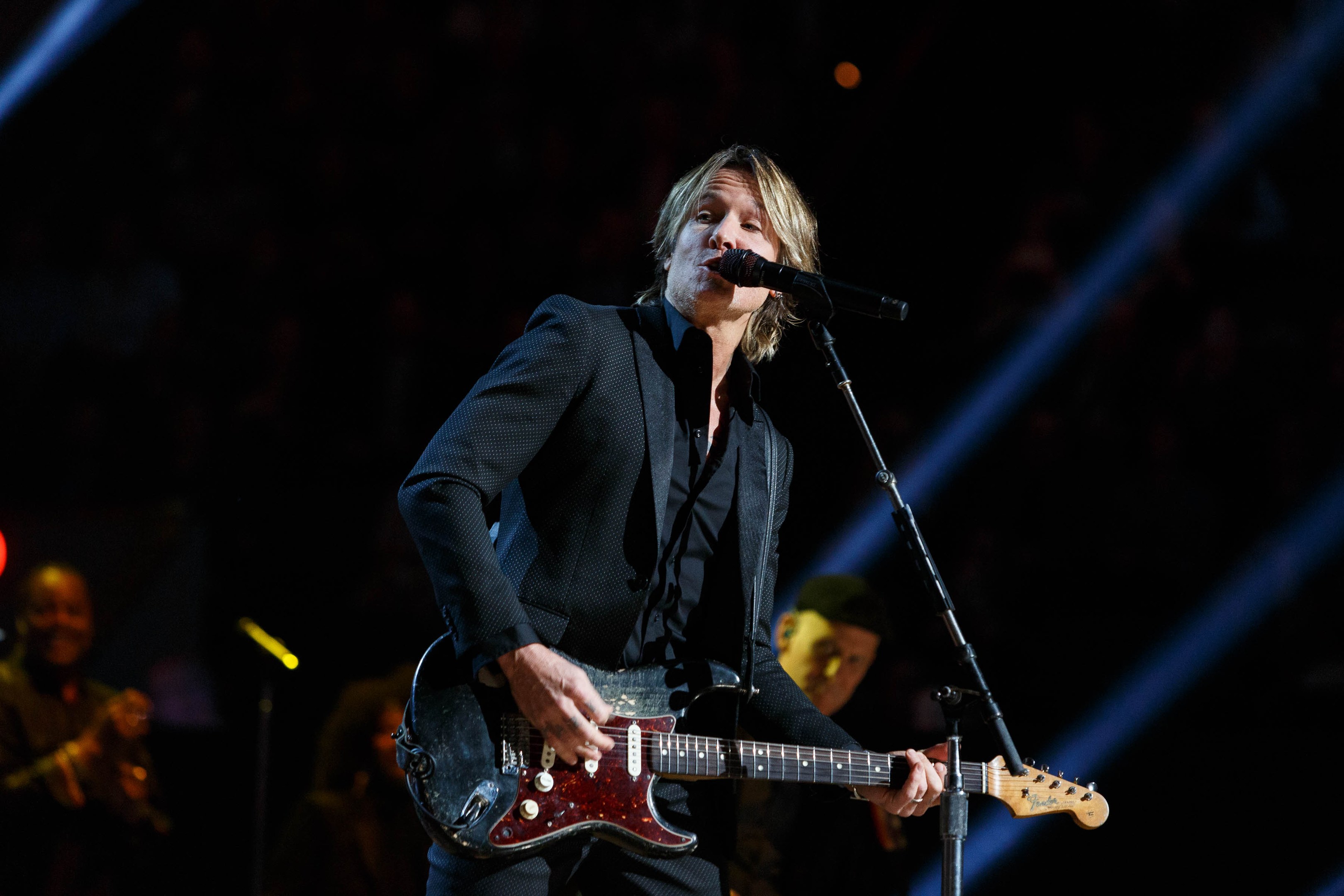 Keith Urban performs auf der Bühne im Joint in Las Vegas, spielt eine Gitarre mit einem Mikrofon vor ihm und Musikern im Hintergrund, unter dunkler Beleuchtung.