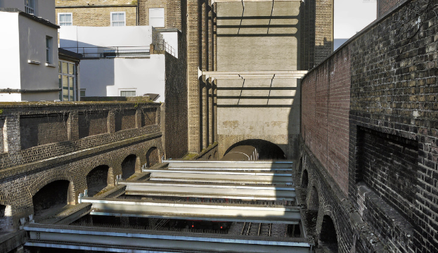 Ein Zug verlässt einen Tunnel, umgeben von Gebäuden.