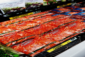 Geschäftsregal mit verschiedenen Lebensmittelpackungen, darunter Gemüse, jeweils mit angebrachten Preisschildern.