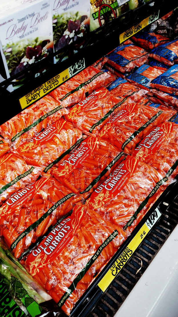 Geschäftsregal mit verschiedenen Lebensmittelpackungen, darunter Gemüse, jeweils mit angebrachten Preisschildern.