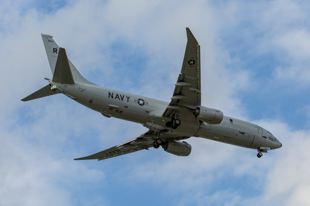 Ein großes Militärflugzeug mit Text und Zahlen, das als Joint Direct Attack Munition bezeichnet wird, fliegt durch einen blauen Himmel mit weißen Wolken.