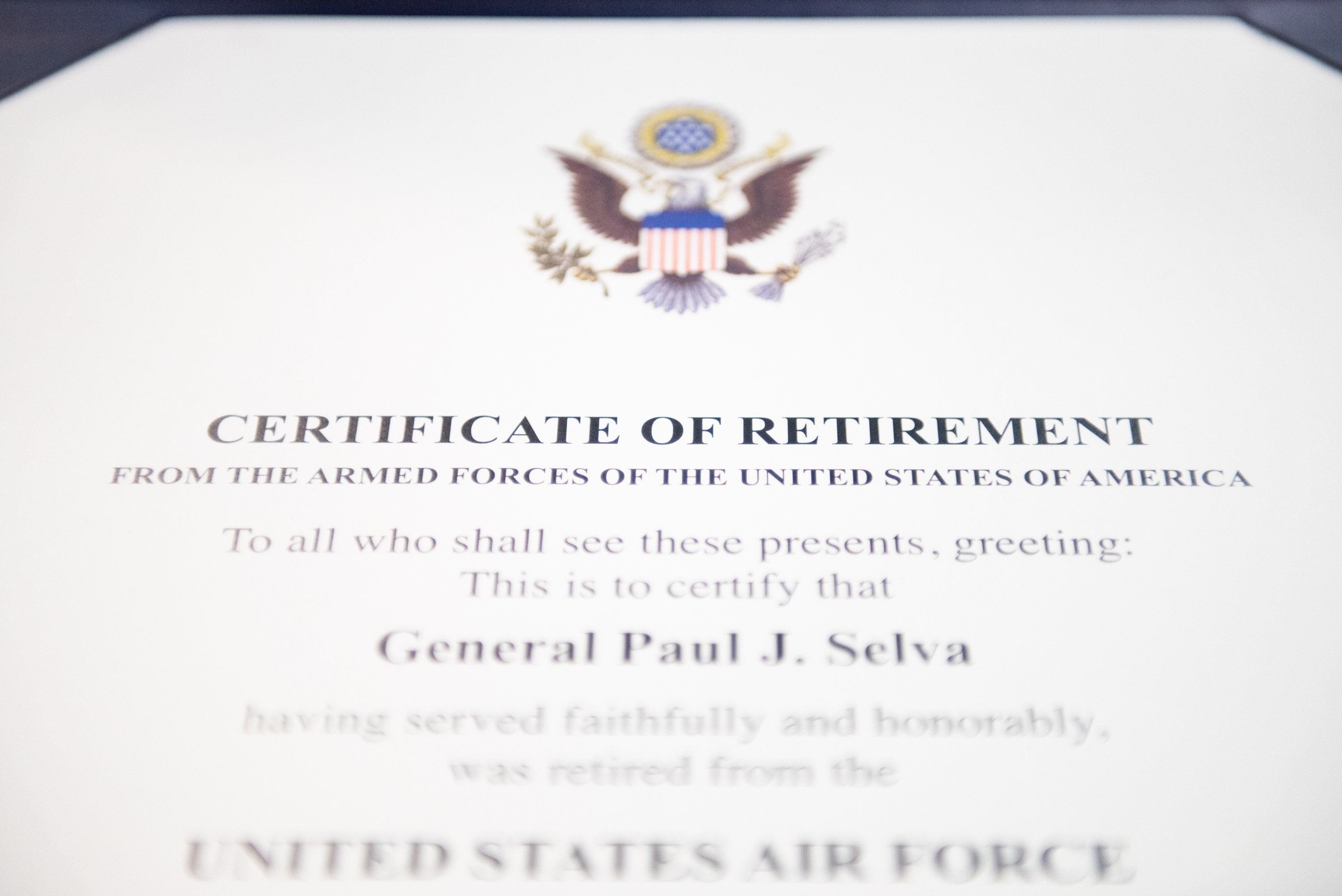 Rahmenurkunde für den Ruhestand der United States Air Force mit blauem Rand, zentralem Stern in einem Lorbeerkranz und einem "Ruhestand"-Banner auf einem Schild-Logo, alles in schwarzer Schrift.