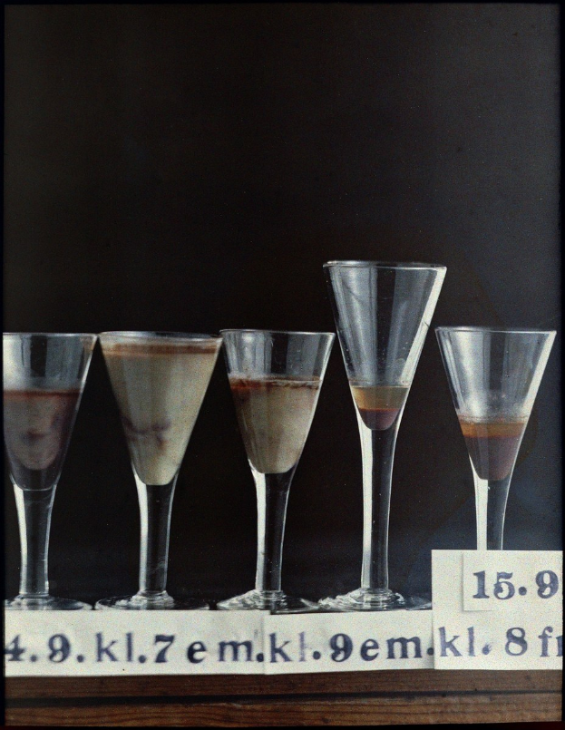 Five martini glasses in a row on a table, each numbered and containing a different drink.