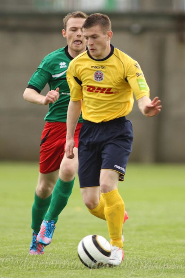 Zwei Männer beim Fußballspiel auf einem grünen Rasen mit einem Ball, mit einem unscharfen Hintergrund und Text unten.