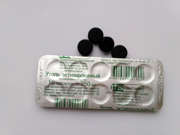 Weißer Tisch mit einer Blisterpackung schwarzer Pillen, mit Text und einem Barcode.