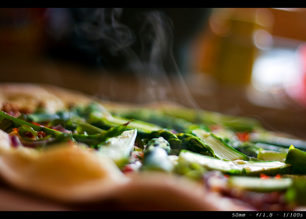 Ein unscharfer Bild von verschiedenen Gemüsen mit Rauch und einem Wasserzeichen in der rechten unteren Ecke.