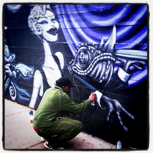 Eine Person hält eine Flasche in der Hand und steht auf einer Straße, umgeben von mehreren anderen Flaschen, mit einer mit Graffiti beschmierten Wand im Hintergrund.