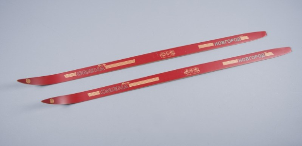 Rote Skier gestapelt auf einer weißen Oberfläche mit Text, der die Marke oder Art angibt.