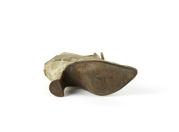 Nahaufnahme eines Paares dunkler Lederschuhe mit gerundeter Spitze, niedrigem Absatz und leicht abgelaufener Sohle auf einem weißen Hintergrund.