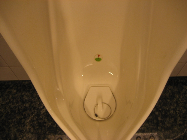 Eine weiße Wandurinal mit Porzellanschüssel und Chromspülung.