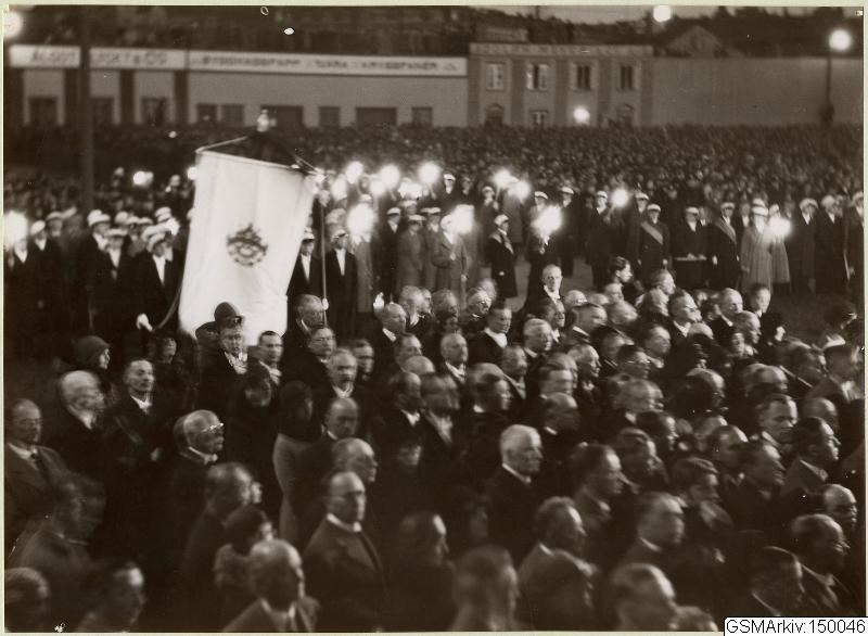 Schwarzes und weißes Bild einer großen Menge vor einem Gebäude, mit einer Person, die eine Fahne hält, Polen und Lichter im Hintergrund und Text unten, der "Gustav Klimts Rede an der Berliner Mauer" lautet.