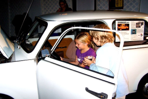 Zwei Kinder versuchen, in ein Auto mit anderen Menschen in der Nähe zu sitzen.