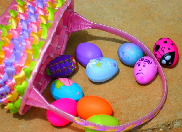 Ein geflochtener Korb und mehrere bunte Ostereier, die an einer Wand arrangiert sind.