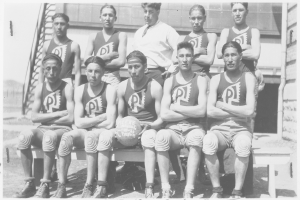 Ein Schwarz-Weiß-Foto einer Basketballmannschaft, die auf einer Bank sitzt, mit einem Mann in der Mitte, der einen Ball hält, und Text am unteren Bildrand.