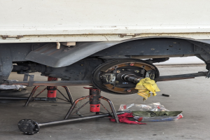 Ein Lastwagen, der in einer Garage geparkt ist und von einem gelben Tuch bedeckt wird, umgeben von verstreuten Werkzeugen und Gegenständen auf dem Boden.