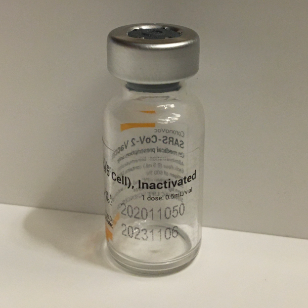 Ein weißes Fläschchen, das mit 'Inaktivierter S-Voc-2A2' beschriftet ist und eine klare Flüssigkeit enthält, auf einem weißen Tisch.