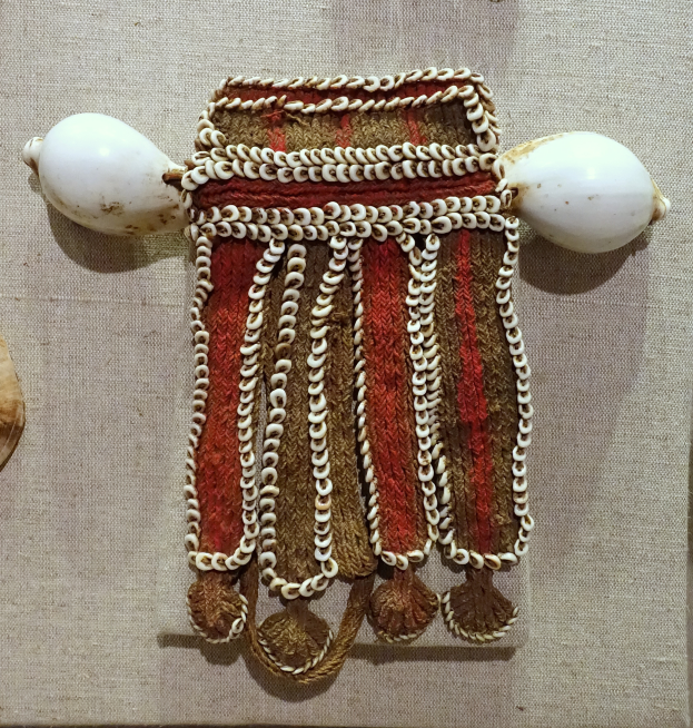 Nahaufnahme eines Kunstwerks in einem Museum, das ein Tuch mit einigen daran befestigten Gegenst├╝cken zeigt, was ihm ein einzigartiges und detailreiches Aussehen verleiht.