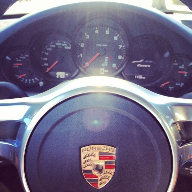 Ein Detailbild des Armaturenbretts eines Porsche Wagens, das den Tacho und das Lenkrad zeigt.