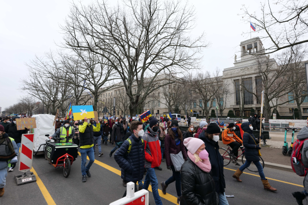 Eine große Gruppe von Menschen marschiert bei einer Demonstration in Washington, D.C. am 21. Januar 2020, einige halten Schilder und andere fahren Fahrräder, mit Bäumen und einem klaren blauen Himmel im Hintergrund.