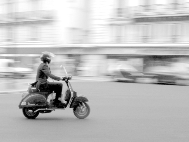 Eine Person auf einem Scooter auf einer Straße.