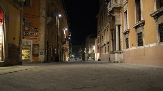 Eine Nachtansicht der Straße mit Gebäuden auf beiden Seiten, einem Geschäft auf der linken Seite und Lichtern in der Mitte.