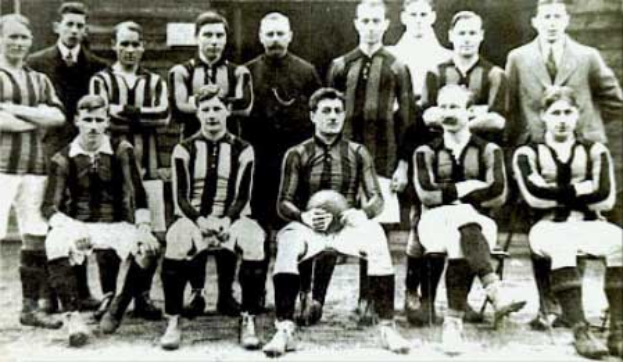 Ein Schwarz-Weiß-Foto einer Fußballmannschaft, mit einigen stehenden und einigen sitzenden Spielern vor einer Wand, mit dem Text "Ballymena Football Club" unten.