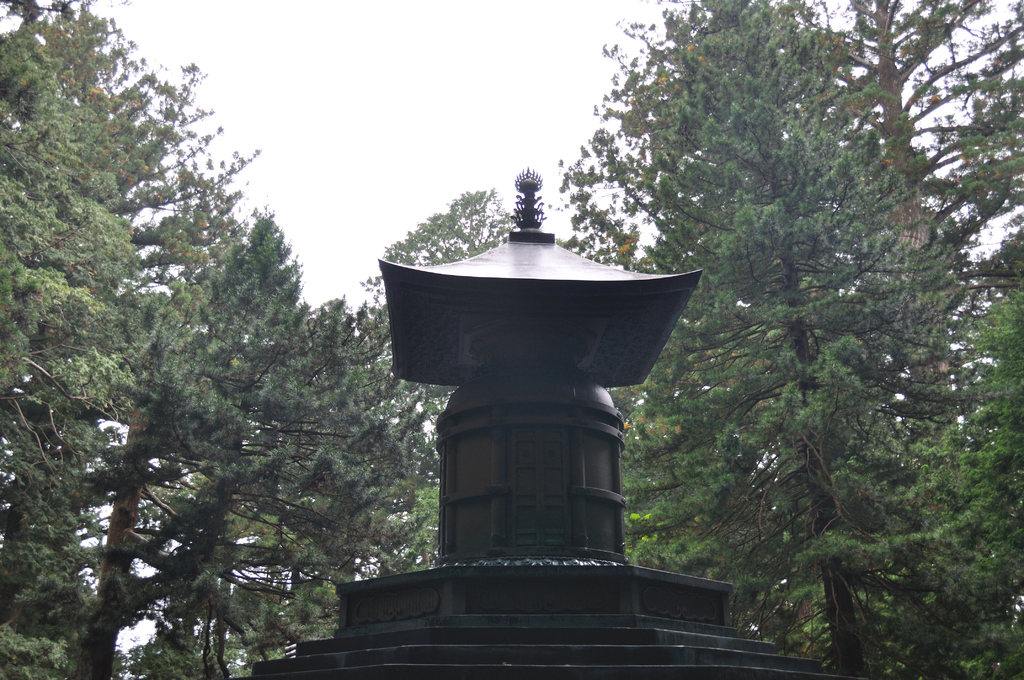 Ein schwarzes Denkmal steht in der Mitte mit Bäumen und Himmel im Hintergrund.