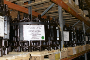 Ein Lagerraum voller metallener Objekte auf Holzpaletten, jedes mit einem Aufkleber versehen, die Teil eines Verteilergehäuses zu sein scheinen.