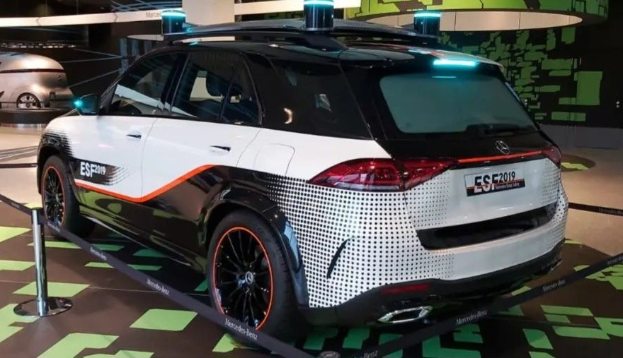 Ein Mercedes-Benz E-Klasse Electric SUV auf der Internationalen Automobil-Ausstellung in Frankfurt, umgeben von Absperrpfosten mit Seilen und Lichtern, mit einem weiteren Fahrzeug und einer textbedeckten Wand im Hintergrund.