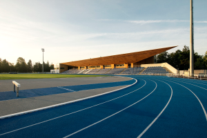 Eine blaue Laufbahn an der University of California, Berkeley, mit einer hölzernen Struktur in der Mitte, umgeben von Gras, Pfählen, Lampen und Bäumen, unter einem bewölkten Himmel.
