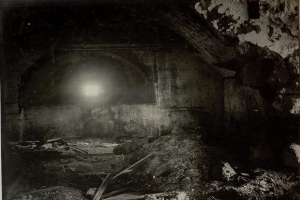 Ein altes Schwarz-Weiß-Foto eines zerfallenden Tunnels mit Schutt auf dem Boden, das eine Lampe am Ende zeigt, befindet sich in den Ruinen der Berliner Mauer.