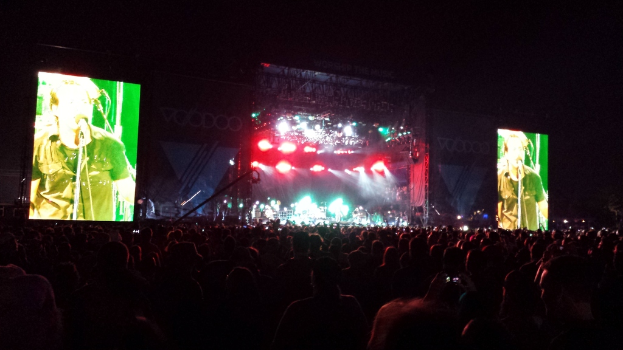 Ein Konzert mit einer Menge unten und einem großen Bildschirm links und einem kleineren rechts.