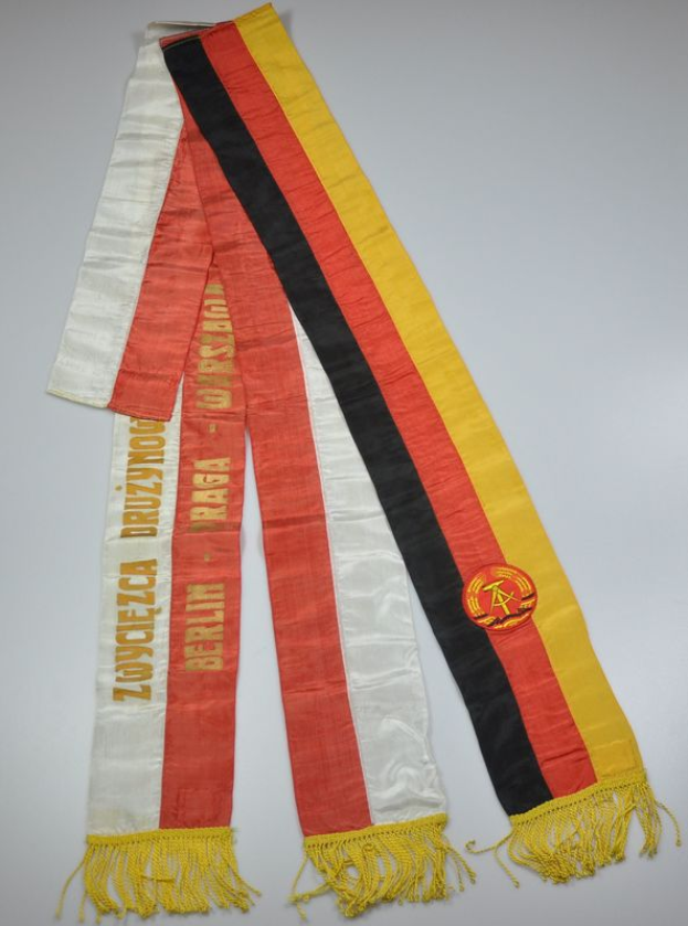 Ein roter, gelber und schwarzer gestreifter Schal mit dem Logo der deutschen Nationalmannschaft auf einer weißen Oberfläche.