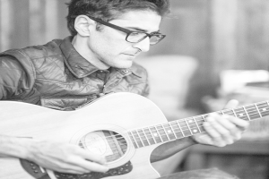 Ein Mann in einer Jacke spielt die Gitarre.