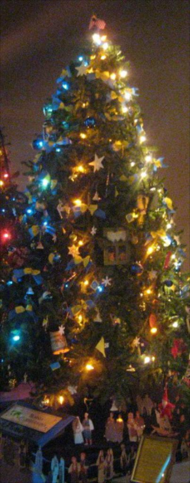 Ein geschm├╝ckter Weihnachtsbaum mit Menschenfiguren auf einem darunter platzierten Tisch.