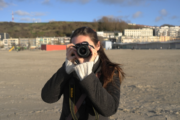 Eine Frau mit einer Kamera vor Gebäuden.